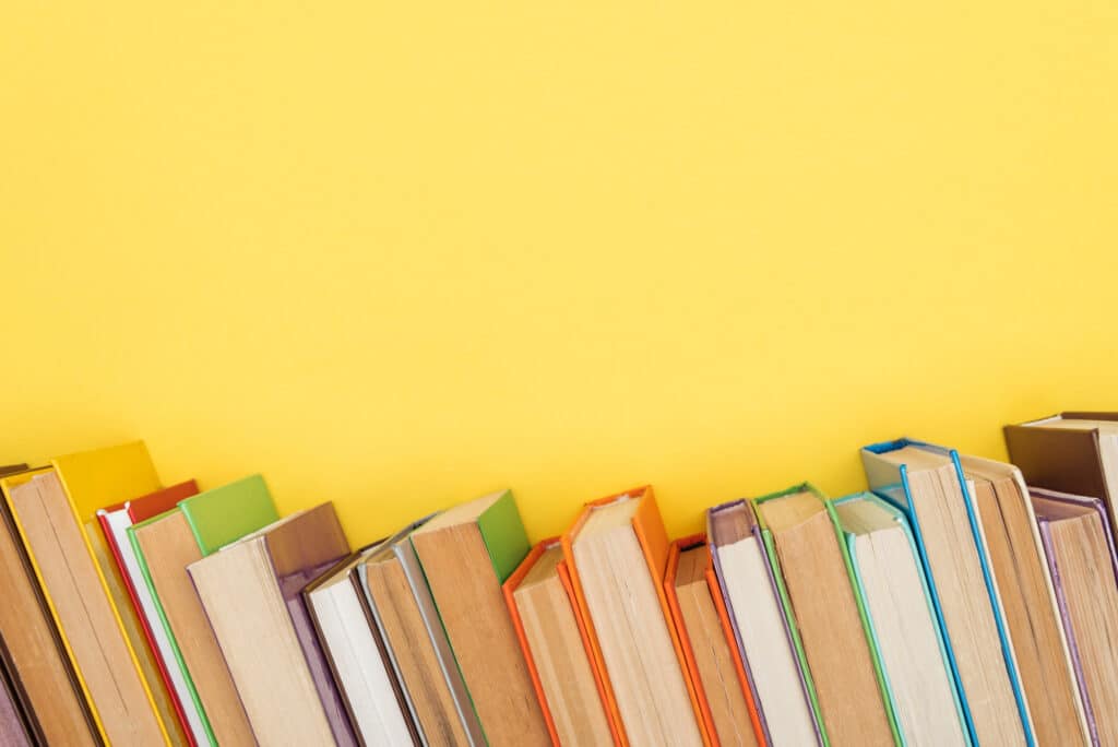 row of books with yellow background. Here are the 10 best books on house flipping so that you can make a lot of money.